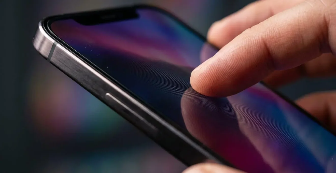 Main tenant un smartphone avec des ondes concentriques symbolisant la vibration haptique